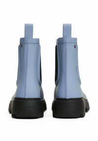 Bottes de cheville en caoutchouc bleu avec des semelles noires texturées, des panneaux latéraux élastiques et des languettes à l'arrière. Présente un petit détail de logo sur le côté.