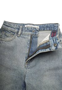 Vaaleansiniset farkut, joissa on vetoketjuluukku, napitus ja kaksi etutaskua. Kangas on haalistunut, ja siinä on hienovaraisia kulutuksia ja tekstuuria.