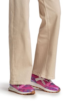 Roze en paarse sportschoenen met mesh- en synthetische texturen, voorzien van een witte zool en diagonale zilveren accenten. Beige rechte pijpen broek.