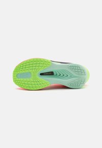 Schuhsohle aus strukturiertem grünem Gummi, rosaner Akzent an der Ferse und ein geformtes Design mit der "FLYPLATE"-Markierung in der Mitte.