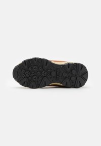 Sole in gomma nera con motivi testurizzati e fori di drenaggio; intersuola marrone e beige che offre ammortizzazione. Logo del brand chiaramente visibile.