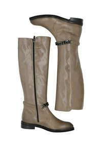 Wysokie buty z taupe'owej skóry z czarnym suwakem po boku oraz dekoracyjnym czarnym paskiem łańcuchowym nad kostką, z płaską czarną podeszwą.