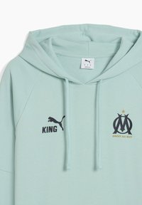 Lys mintgrøn hoodie med kængurulomme, prydet med et sort Puma-logo, teksten "KING" og Marseille-emblemet med guldstjernedetalje.