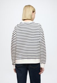 Bluza w paski w kremowym i granatowym kolorze, z długimi rękawami, ściągaczami na mankietach i luźnym krojem. Widok z tyłu pokazuje poziome paski i szczegóły szwów.