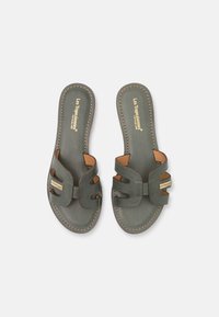 Groene leren sandalen met twee horizontale banden, tan accenten en decoratieve stiksels langs de randen. Gemaakt met een gouden merk op de binnenzool.