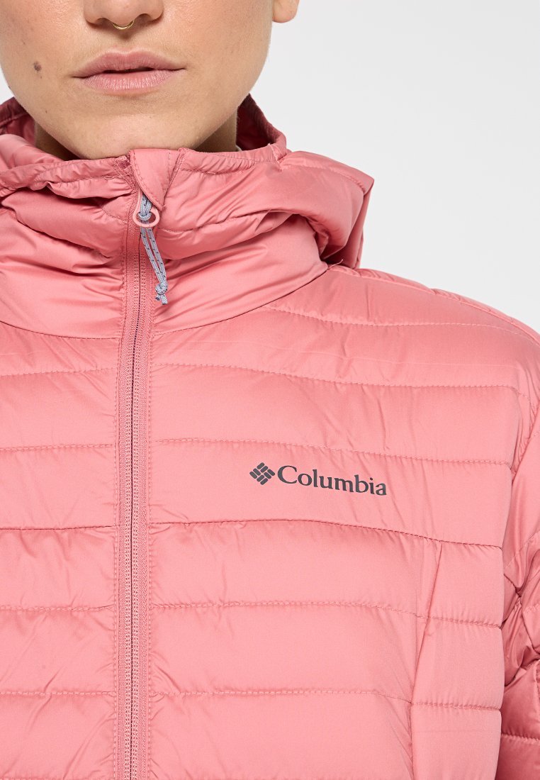 Giacca isolante rosa chiaro con cuciture orizzontali, colletto alto e zip a lunghezza completa. Presenta il logo Columbia sul petto.