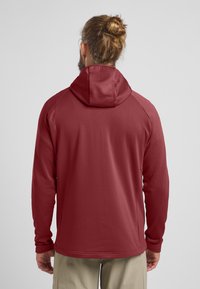 Rode longsleeve hoodie met een textuurpatroon, met raglanmouwen en een relaxte pasvorm. De stof lijkt ademend en lichtgewicht te zijn.
