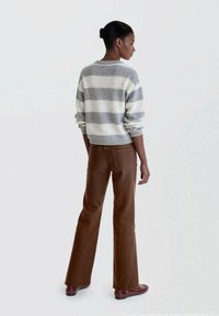 Grå och vit randig tröja med ribbade ärmslut, matchad med bruna vida byxor. Outfiten har en avslappnad passform och mjuk textur.