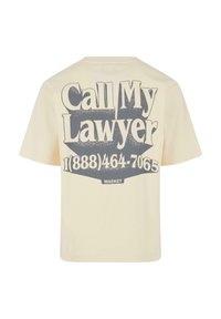 Cremefarvet T-shirt med korte ærmer, der har et stort grafisk motiv i sort skrift, som siger "Ring til min advokat" med et telefonnummer nedenunder.