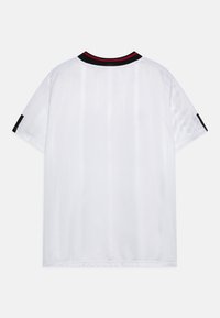 Bílý sportovní dres s vertikálními pruhy, černým a červeným límcem, krátkými rukávy s černými akcenty a hladkou, lesklou texturou látky.