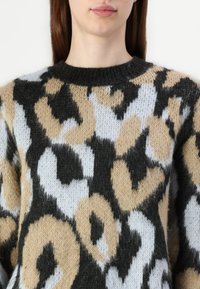 Knit sweater featuring a black, beige, and light blue abstract leopard print. Textured, soft material with a classic round neckline.