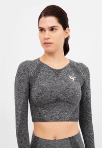 Long-sleeve, cropped athletic top in dark gray melange fabric with textured pattern; features a small white logo on the chest.