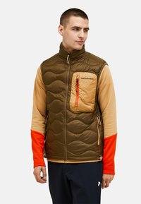 Isolierte Weste in Olivgrün und Beige, mit einem gesteppten Design, einer Reißverschlusstasche auf der Brust mit orangefarbenen Akzenten und langen orangefarbenen Ärmeln.