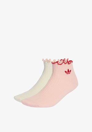 Deux paires de chaussettes courtes : une rose clair avec un bord volanté rouge et un logo, l'autre crème douce avec un bord volanté assorti.