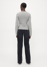 Gray knit sweater with a fitted waist and long sleeves, paired with black wide-leg jeans featuring a classic five-pocket design.