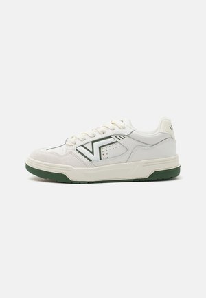 White sneaker with green accents, featuring a smooth leather upper, suede toe cap, and perforated detailing. Rubber sole with grip pattern.