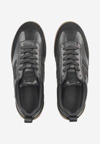 Sneakers neri con una tomaia in pelle e camoscio, lacci neri piatti, suola in gomma e un pratico occhiello sul retro per indossarli facilmente.