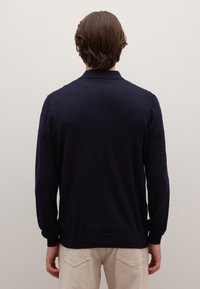 Marineblauwe cardigan gemaakt van zachte gebreide stof. Voorzien van een klassieke kraag, lange mouwen en geribbelde boorden, met een glad oppervlak en zonder versieringen.