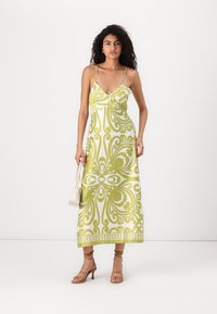 Vestido maxi em branco e verde claro com um padrão floral. Apresenta alças finas e uma textura suave. Combine com sapatos de salto bejes e uma bolsa de mão.