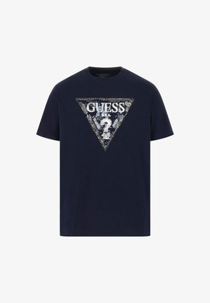 Navyblauwe katoenen t-shirt met een driehoekige grafiek waarop het "GUESS" logo, een vraagteken en bloemaccenten in wit en zilver zijn afgebeeld. Korte mouwen.