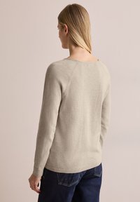 Beige Strickpullover mit Rundhalsausschnitt, gerippten Bündchen und entspannter Passform. Die Rückansicht zeigt eine glatte Textur und ein schlichtes Design.