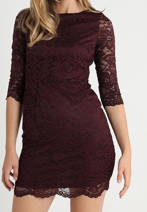 Bordowa koronkowa sukienka z rękawami do łokcia, kwiatowym wzorem, falowanym dołem i dopasowanym krojem, ukazująca misterną teksturę i detale.