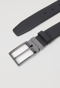 Schwarzer Ledergürtel mit strukturiertem Oberflächendesign, rechteckiger silberfarbener Metallschnalle und einem Schiebemechanismus zur Größenanpassung.