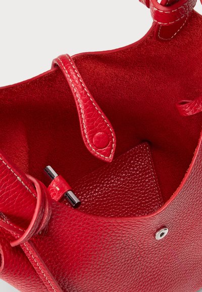 Sarkans ādas roku maciņš ar teksturētu virsmu, kuram ir gluda iekšējā oderējums, spiedpogu aizdare un pulēti aparatūras akcenti.