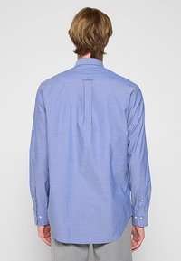 Helleblaue Langarmbluse mit einem Button-Down-Kragen, Rückenfalte und geknöpften Manschetten. Hergestellt aus strukturiertem Baumwollstoff.