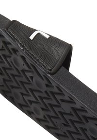 Sort sandal med en tekstureret overrem og mønstret sål. Har et fremtrædende logo på remmen og en robust gummikonstruktion.
