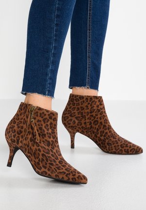 Stivaletti alla caviglia con stampa leopardata in suede marrone, con punta appuntita, tacco di 5 cm e cerniere laterali. Design aderente con superficie texturizzata e senza loghi visibili.