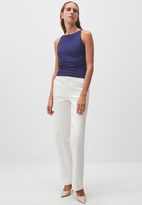 Top viola senza maniche, pantaloni bianchi a gamba dritta e scarpe beige chiaro. Tessuto morbido, design aderente e stile minimalista.