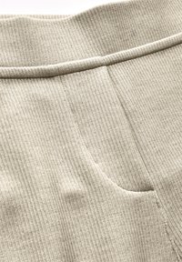 Ljusbeige ribbat tyg med en bred elastisk midja och subtila fickdetaljer. Mjuk textur med vertikala linjer genom hela tyget.