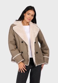 Brown double-breasted jacket with a cream faux fur collar and trim. Features black buttons and a relaxed fit with visible stitching accents.
