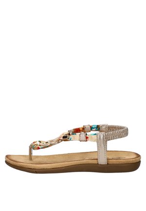 Sandale plate avec une semelle en faux cuir beige, des brides à motif floral, des accents métalliques et un enroulement texturé à la cheville pour le soutien.