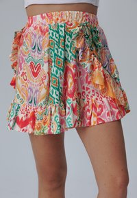 Kleurrijke gestreepte rok met een ruffles taille en zoom. Bevat roze, oranje, groene en paarse ontwerpen op lichte stof.