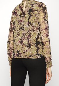 Blumenbluse aus leichtem Stoff, mit einem Schlüsselrückenausschnitt, langen Ärmeln mit gerafften Bündchen und einer Mischung aus grünen und lila Farbtönen.