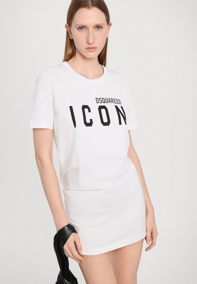 T-shirt en coton blanc avec un texte graphique noir "DSQUARED2 ICON". Col rond, manches courtes, style ajusté. Le modèle tient un article en cuir noir.