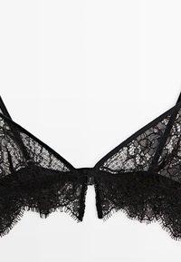 Black lace bra featuring floral patterns, scalloped edges, adjustable straps, and a hook-and-eye closure at the back. Soft texture.