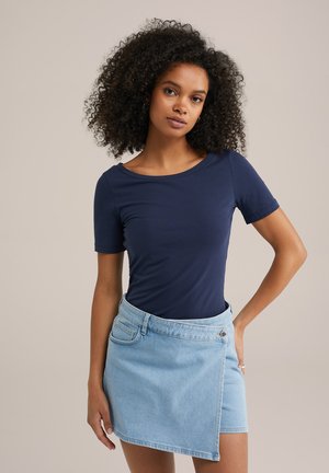 Navy short-sleeve top paired with a light blue wrap denim skirt featuring a side pocket and metal button detail.