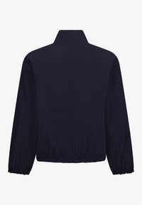 Giacca navy con colletto rialzato, polsini elasticizzati e superficie testurizzata. Il design semplice presenta una cucitura orizzontale sulla schiena.