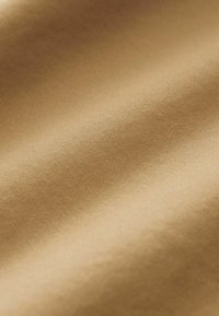 Beige fabric showcasing a smooth texture with a subtle sheen, featuring fine, consistent ribbing patterns across the surface.