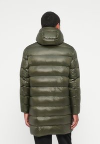 Giacca puffer verde oliva con finitura lucida, motivo trapuntato orizzontale e cappuccio staccabile. Maniche lunghe e taglio a lunghezza intermedia.