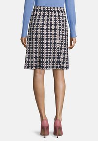 Joustavavyötäröinen, kukkakuvioinen hame laivastonsinisessä, jossa vaaleanpunaisia ja kermaisia yksityiskohtia. Sileä, kevyt kangas laskeutuu puolipitkään helmaan, yhdistetty vaaleanpunaisiin korkkareihin.