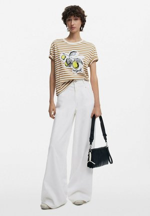Striped beige and white t-shirt with lemon graphic, paired with wide-leg white trousers. Accessorized with a black ribbed handbag.