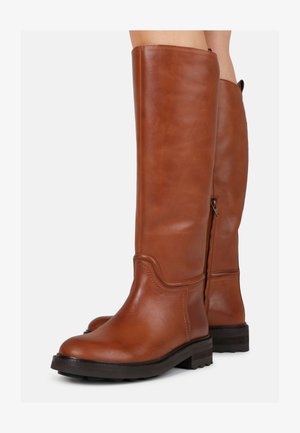 Botas de cuero marrón hasta la rodilla con una textura suave, punta redonda, cremallera lateral y suela de goma negra. Un simple pespunte realza el diseño.