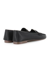 Mocasines de cuero negro con un acabado texturizado, presentando una suela plana y detalles bordados en la parte delantera. Diseño minimalista, silueta elegante.