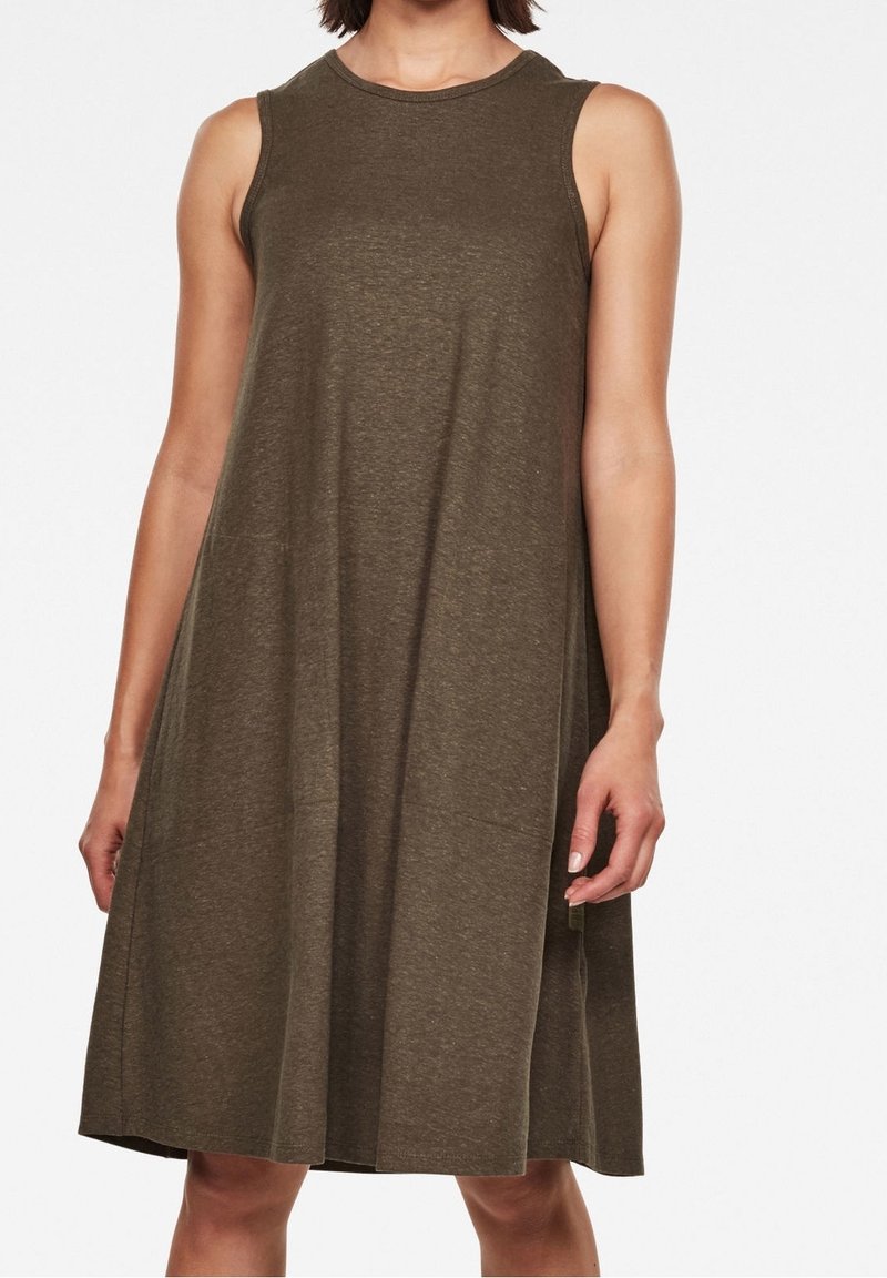 Femme portant une robe kaki sans manches, longueur genou, coupe ample, sur fond blanc.