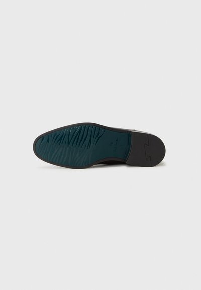 Semelle de chaussure noire avec un motif en caoutchouc texturé teal et des accents marron. Présente une bordure lisse et un design de bout arrondi.