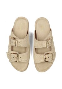 Beige suède slippers met twee verstelbare banden met gouden gespen en een textuurstiksel langs de randen. Gladde voetbed.